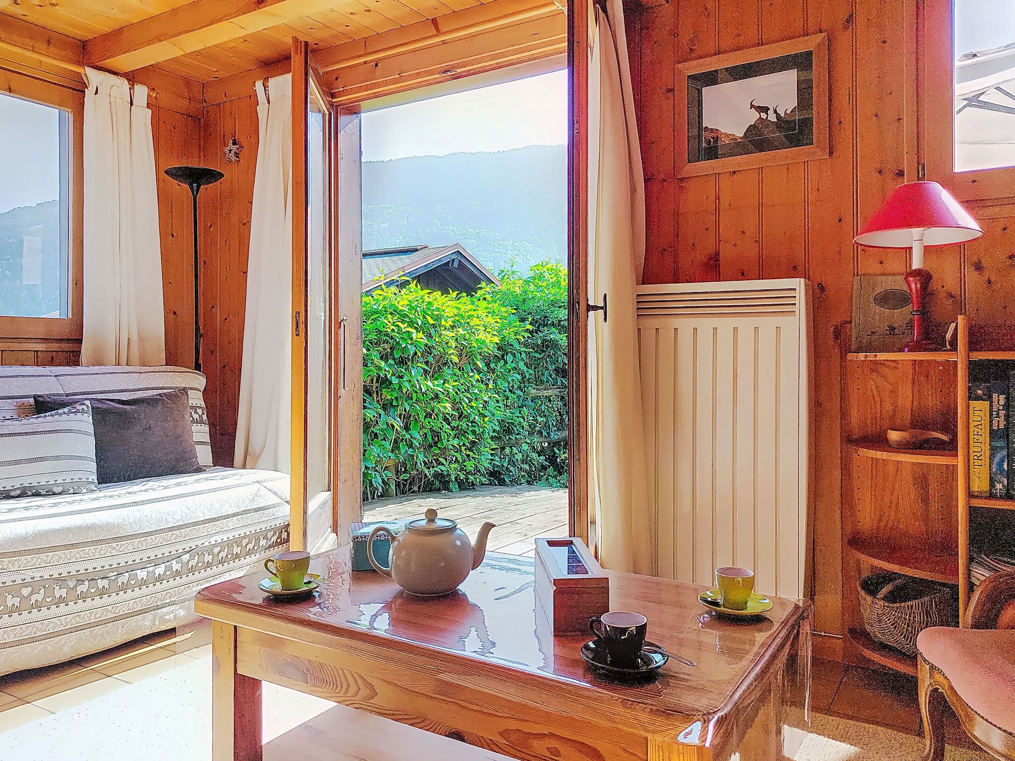 Una habitación acogedora con una cama, una mesa con tetera y tazas, un radiador y una estantería.