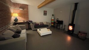 Ein gemütliches Wohnzimmer mit Backsteinwand, einer Couch, einem Couchtisch, einem Kamin und einem kleinen Beistelltisch mit Lampe.