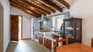 A kitchen with wooden beams, a dining table, and a cabinet with dishes.