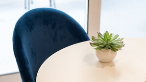 A round table with a potted plant, a blue chair, and a window in the background. - Luxury Studio w/ Backyard Near Plaka & Acropolis 3 (Athens)