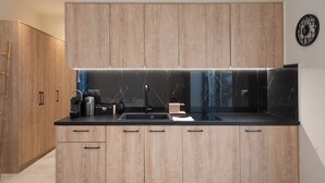 A modern kitchen with wooden cabinets, a black countertop, and a built-in stove. - Luxury Studio w/ Backyard Near Plaka & Acropolis 3 (Athens)