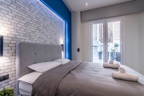 Un dormitorio moderno con pared de ladrillo, una cama grande y vistas al exterior.