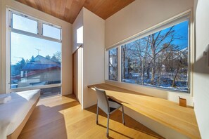 A modern room with a large window, a wooden desk, and a bed. - Chalet Opus (Hakuba)