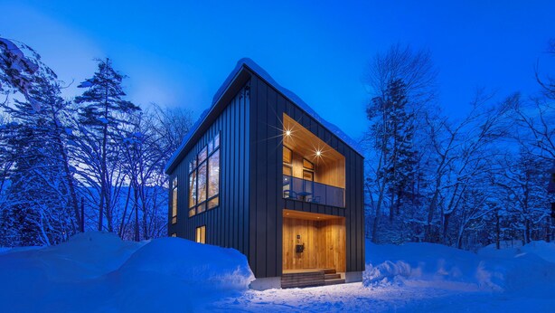 A modern, two-story cabin with a balcony, surrounded by snow-covered trees. - Chalet Opus (Hakuba)