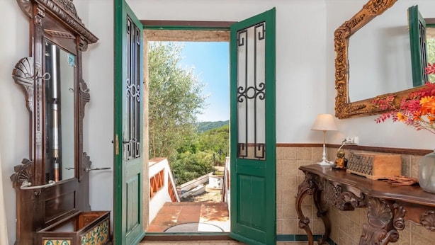 A room with a large mirror, a green door, and a view of greenery outside. - Holiday Home 'Can Garriga, Casa Principal' with Mountain View, Private Terrace and Wi-Fi (Girona)