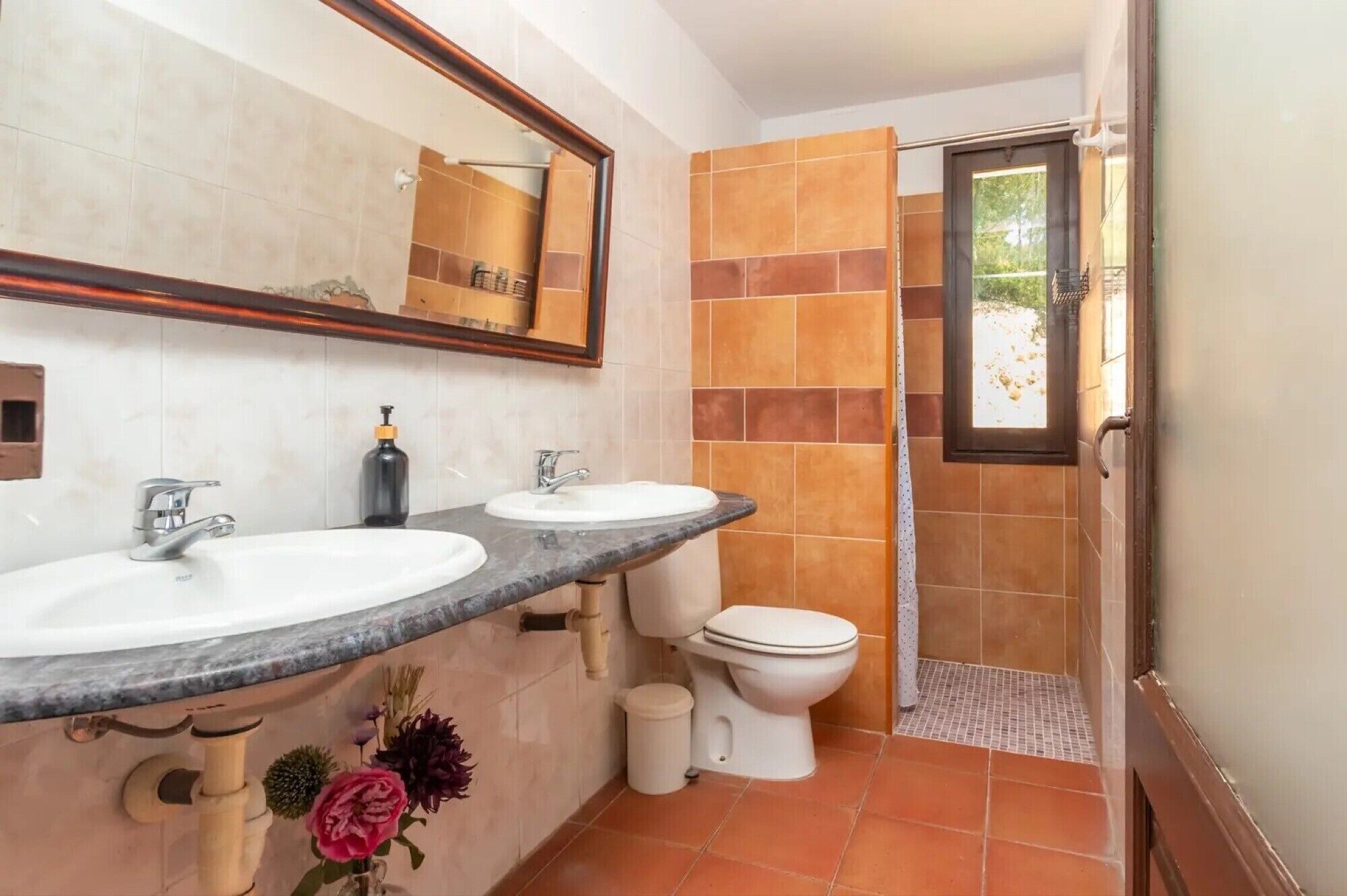 A bathroom with two sinks, a toilet, and a shower area.