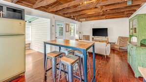 A rustic kitchen with wooden beams, a large table, and bar stools. - Young Street Homes (Panama City Beach)