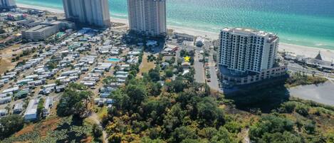 Vista aérea de una zona turística costera con varios edificios de gran altura, una playa y un conjunto denso de construcciones más pequeñas.