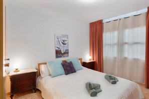 A neatly made bed with pillows, a bedside lamp, and a painting on the wall. - Apartment in Santa Cruz near Beaches (Santa Cruz de la Palma)