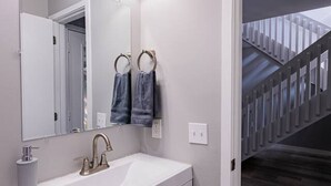 A bathroom with a white sink, a large mirror, and a towel ring.