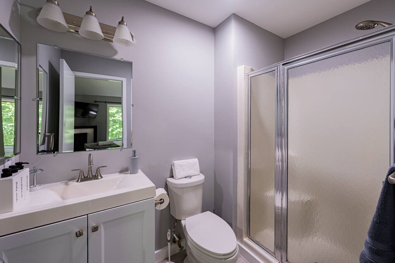 Une salle de bain moderne avec un lavabo blanc, des toilettes et une douche à parois de verre.