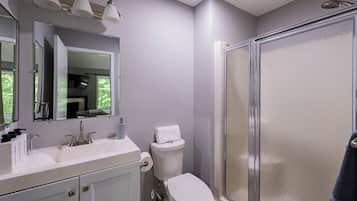 Une salle de bain moderne avec un lavabo blanc, des toilettes et une douche à parois de verre.