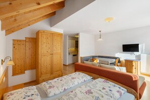 A bedroom with a bed, wooden wardrobe, and a television.