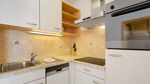Una cocina con lavavajillas, pileta de acero inoxidable y horno integrado.