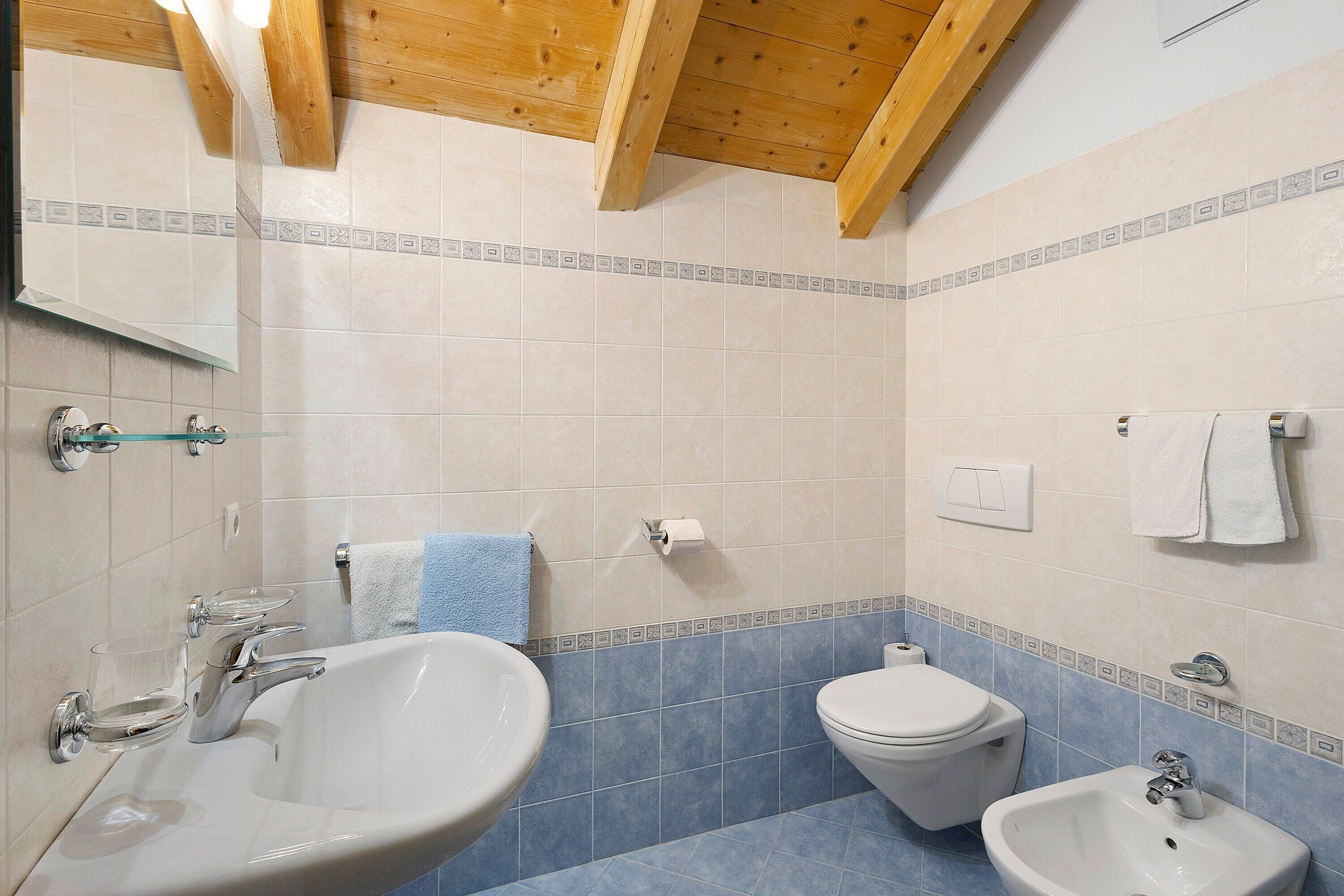 A bathroom with a sink, toilet, bidet, and mirror.