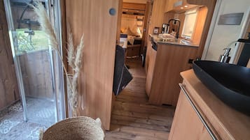En kompakt autocamper indretning med et tekøkken, et spiseområde og soveplads.