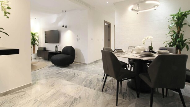 A modern dining area with a marble floor, a round table set for four, and a large potted plant. - Al Yassmine 5-6 Apartment - A True Gem (Sfax)