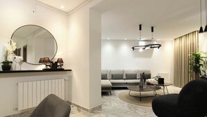 A modern living room with a sofa, armchairs, a coffee table, and a round mirror. - Al Yassmine 5-6 Apartment - A True Gem (Sfax)