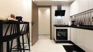 A modern kitchen with white cabinets, a black countertop, and a built-in oven. - Al Yassmine 5-6 Apartment - A True Gem (Sfax)