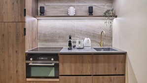 A compact kitchen with a built-in oven, a sink, and a countertop with a kettle and toaster. - Superb air-conditioned flat on the Champs Elysées (Paris)