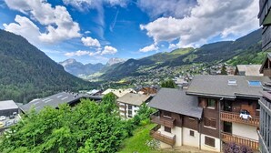 A mountain village with traditional wooden houses, a valley, and distant mountains. - Isabella IS65 VIEW & CENTER 4 Pers. (Châtel)