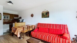 A compact living space with a dining area, a sofa, a kitchen, and a hanging artwork. - Isabella IS65 VIEW & CENTER 4 Pers. (Châtel)