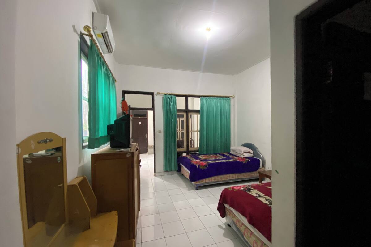 Una habitación con una cama, un escritorio, una silla, un televisor y un armario.