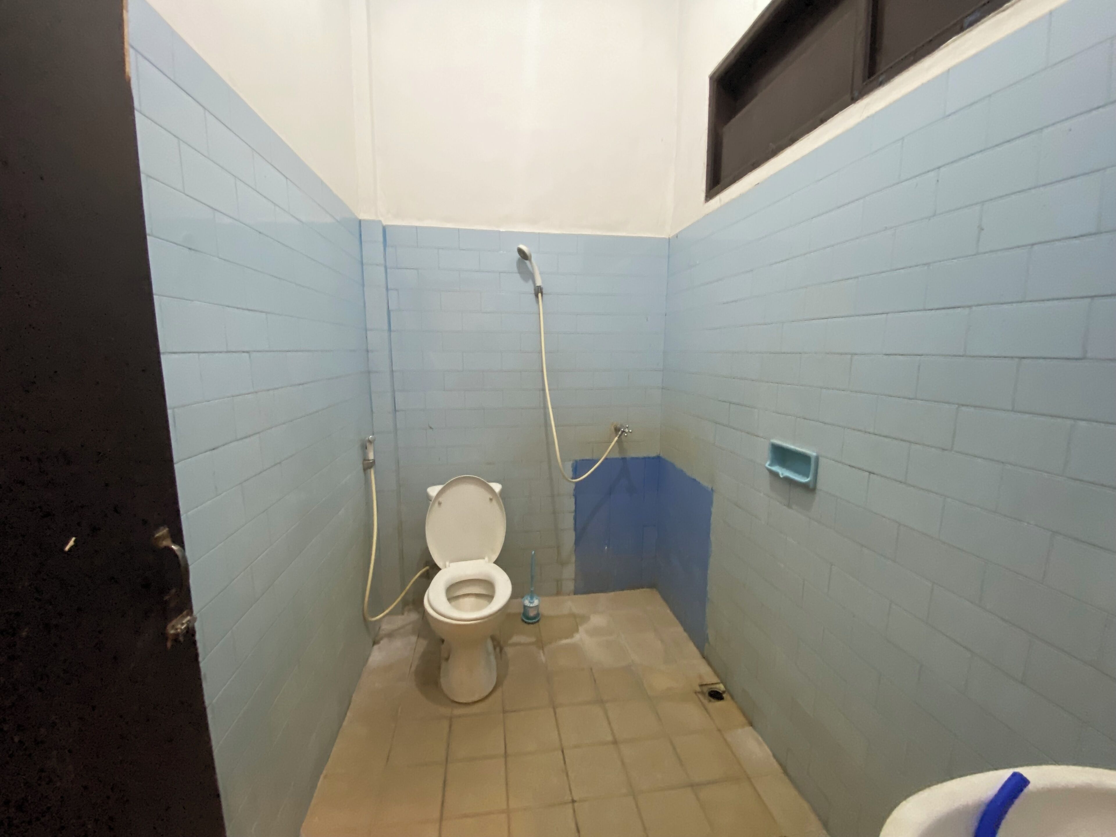A small, tiled bathroom with a toilet, a shower, and a sink.