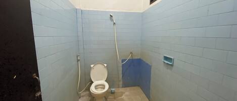 A small, tiled bathroom with a toilet, a shower, and a sink.