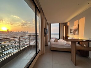 A modern hotel room with a large window offering a city view, a bed, a desk, and a TV. - Gate 9 Tower -Studios & Apts Mar Mikhael (Beirut)