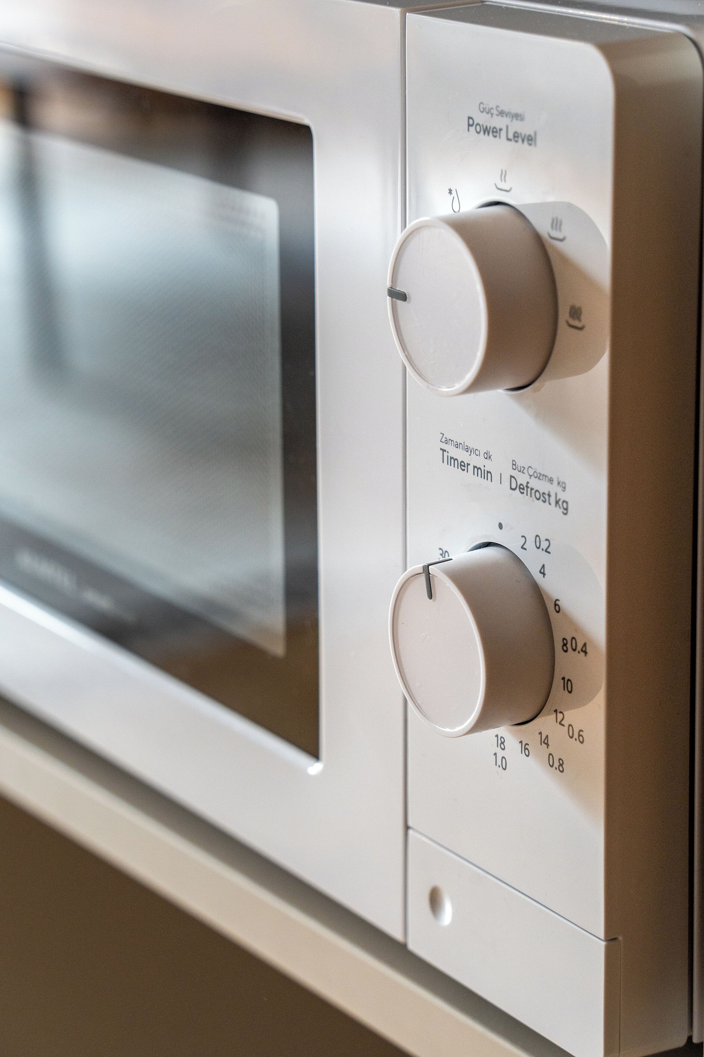 A microwave oven with a digital display and control knobs for power level, timer, and defrost settings.