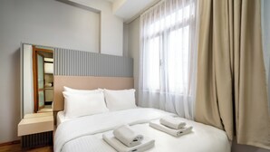 A modern hotel room with a large bed, a bedside table, and a mirror. - Pia Global - Gümüşsuyu (İstanbul)
