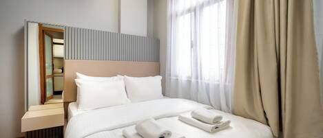 A modern hotel room with a large bed, a bedside table, and a mirror.