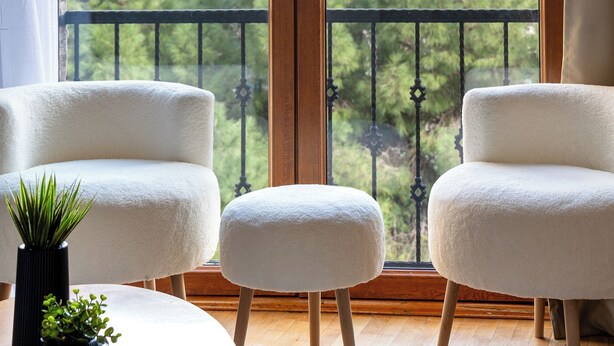 A room with a large sliding glass door leading to a balcony. There are two white chairs and a small round table with a potted plant on it. - Pia Global - Gümüşsuyu (İstanbul)