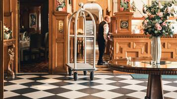 A checkered floor, a round table with a vase, and a man in the background.