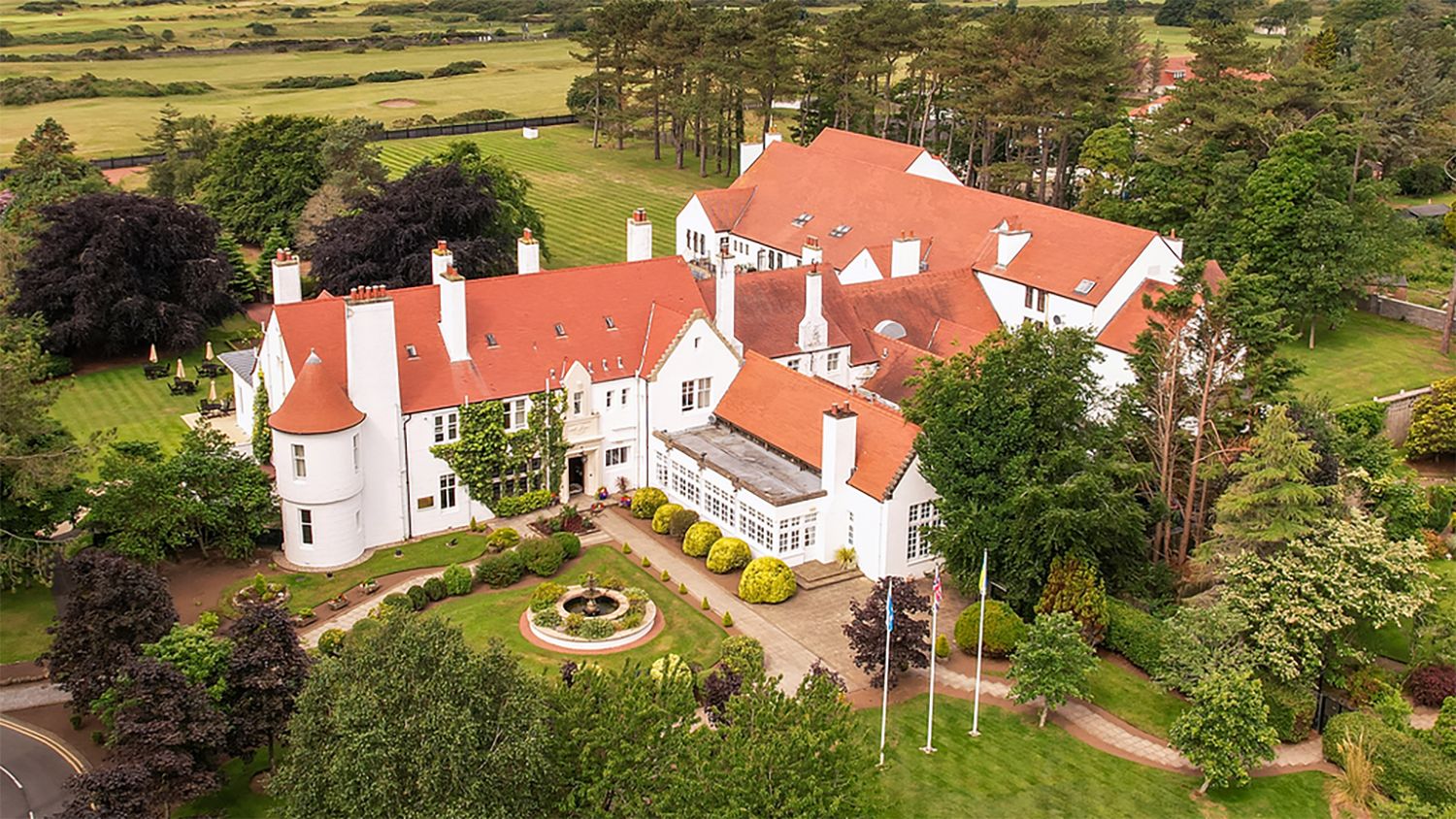 A large estate with multiple buildings, a circular driveway, and well-maintained gardens.