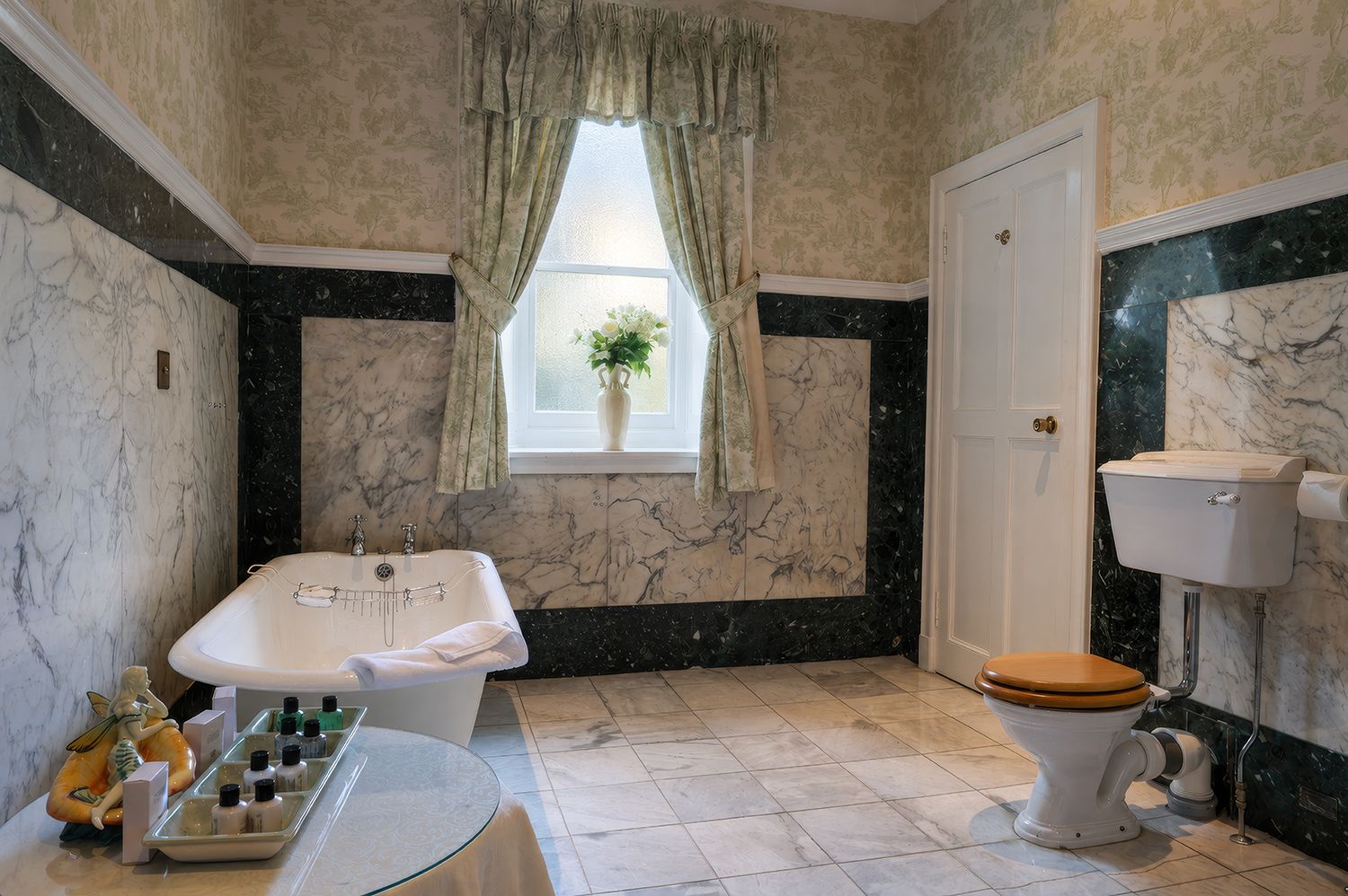 A bathroom with a bathtub, toilet, and a window with curtains.
