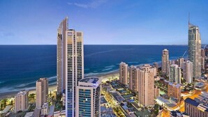 A coastal cityscape with high-rise buildings, including a prominent hotel with a modern design, situated near the beach. - 5-star, 2 bdrm apt with the perfect view of Surfers Paradise beach (Surfers Paradise)
