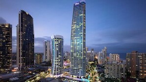 A cityscape with two prominent high-rise buildings, one with a curved facade and the other with a straight design, both featuring illuminated windows and a modern architectural style. - 5-star, 2 bdrm apt with the perfect view of Surfers Paradise beach (Surfers Paradise)