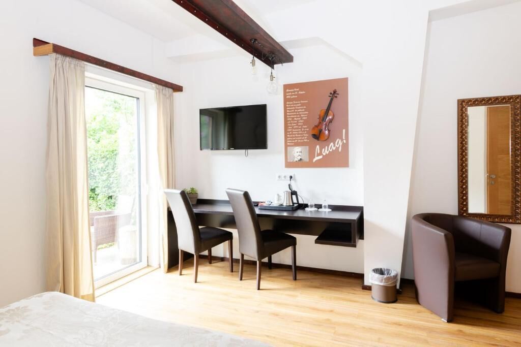 Una habitación moderna con suelo de madera, un escritorio con dos sillas, un televisor, un cartel en la pared y un espejo grande.