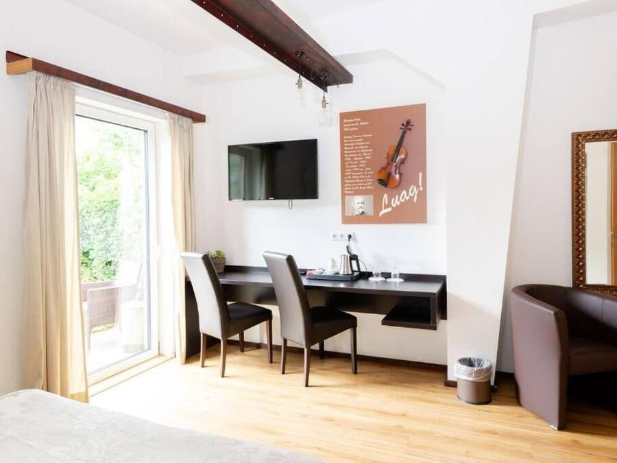 Una habitación moderna con suelo de madera, un escritorio con dos sillas, un televisor, un cartel en la pared y un espejo grande.