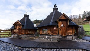 Two wooden cabins with steeply pitched roofs, a wooden deck, and a gravel path. - Biohotel Eggensberger (Fuessen)