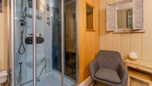 Une salle de bain dotée d’une douche à parois de verre, d’un meuble-lavabo en bois et d’un miroir à volets.