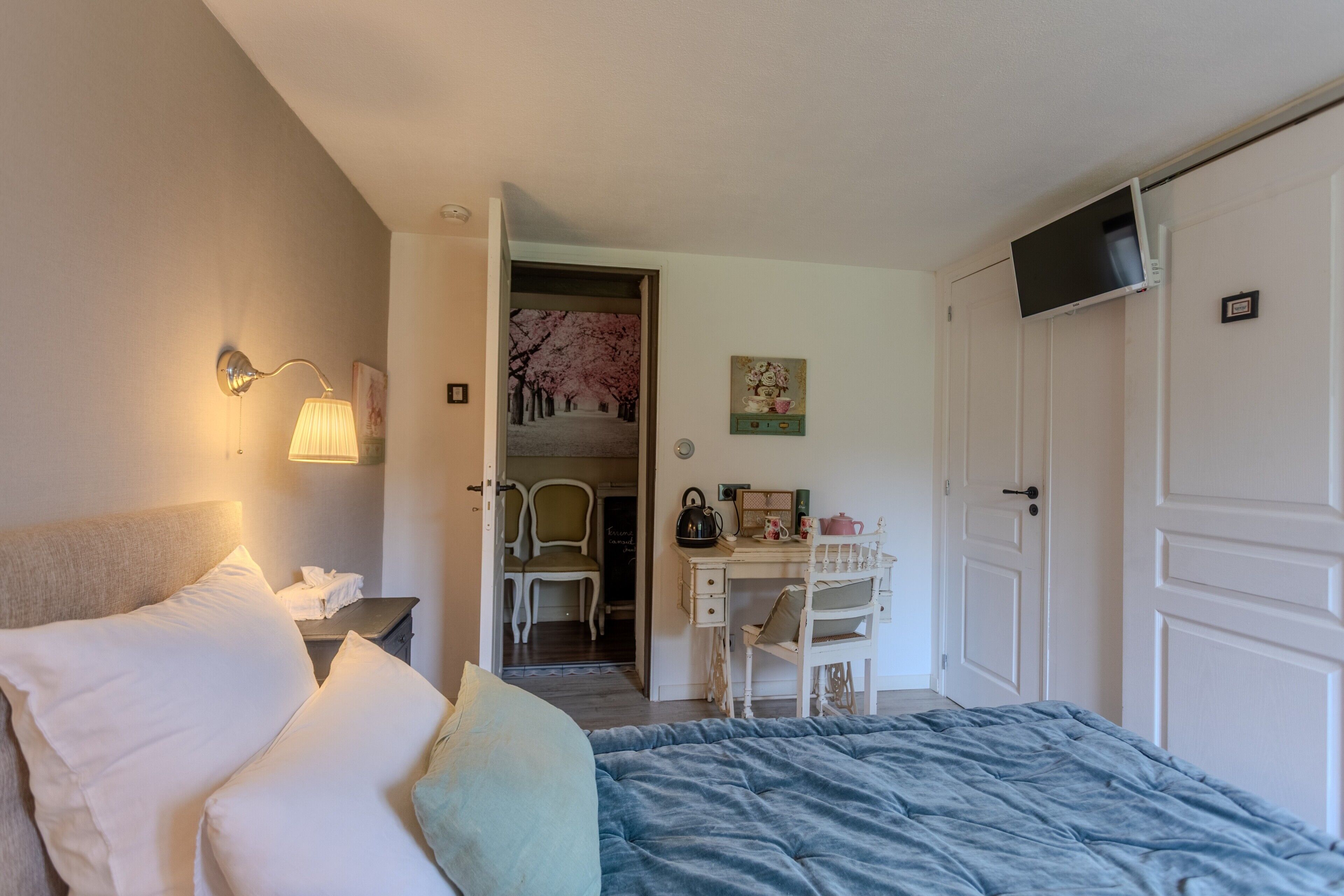 Une chambre à coucher comprenant un lit, une lampe de chevet, un bureau, une chaise et un téléviseur fixé au mur.