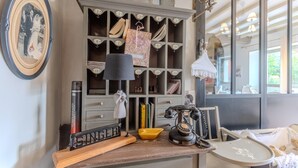 Une cuisine d’époque, avec un plan de travail en bois, un téléphone ancien et une étagère murale où sont exposés divers objets.