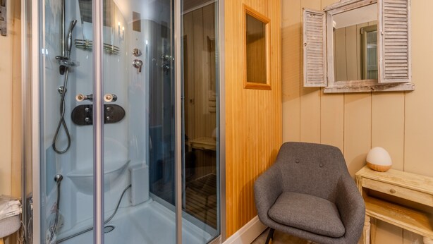 Une salle de bain dotée d’une douche à parois de verre, d’un meuble-lavabo en bois et d’un miroir à volets.