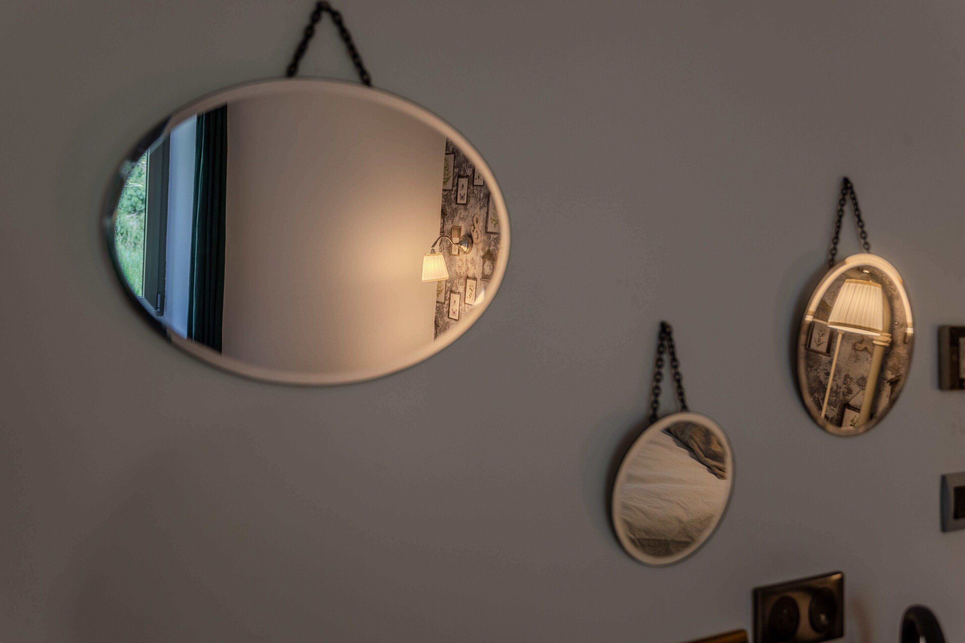 Un mur orné de trois miroirs ovales de tailles différentes, chacun présentant un motif unique et suspendu au plafond.