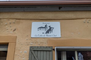 Letrero del restaurante 'La Table de Mamie Chat' en la fachada de un edificio color beige.
