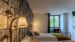 Een slaapkamer met twee bedden, een bureau en een raam met uitzicht op groen.