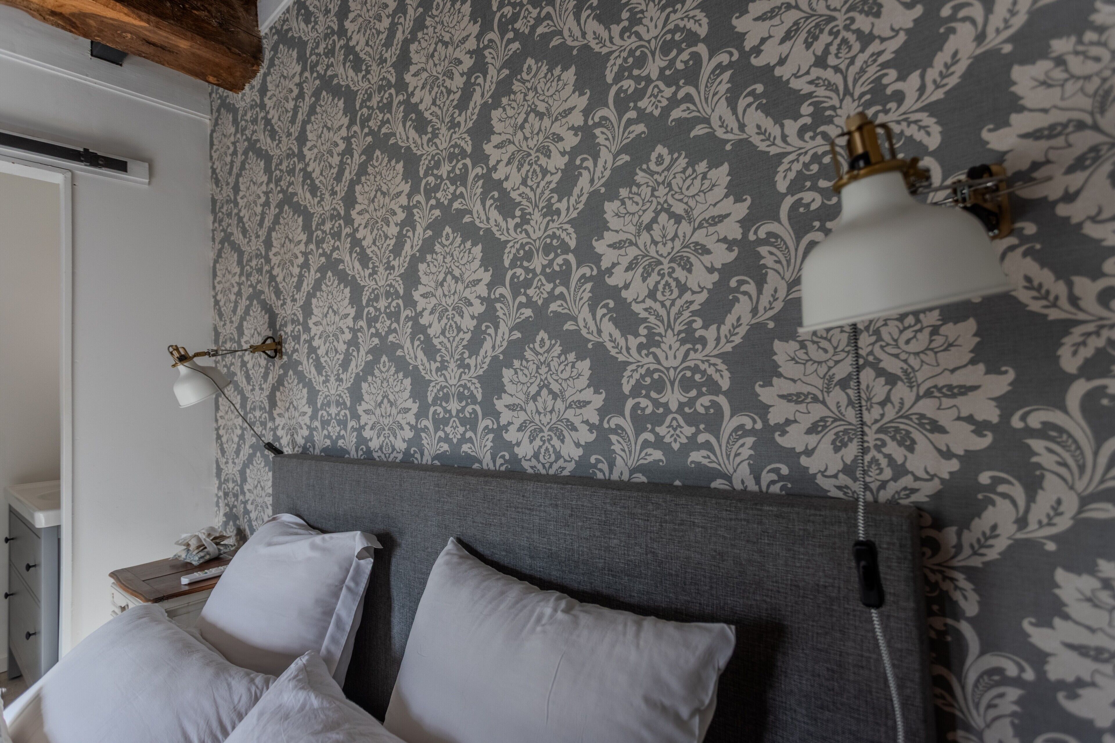 Une chambre à coucher avec un papier peint à motifs, une tête de lit et deux lampes de chevet.